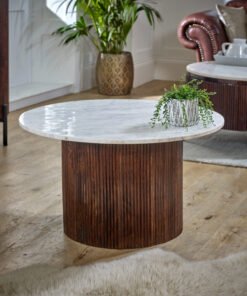 Round Opal Mango Wood Coffee Table with Marble Top featuring a ribbed dark brown base in a stylish living room with plants and a leather chair