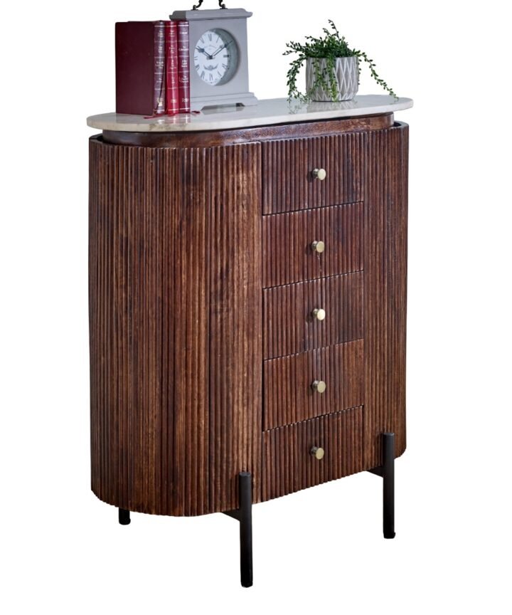 Opal Mango Wood wide chest of drawers with vertical grooves in brown mango wood, topped by a white marble surface, brass knobs, and black metal legs; clock, books, and a plant on top.